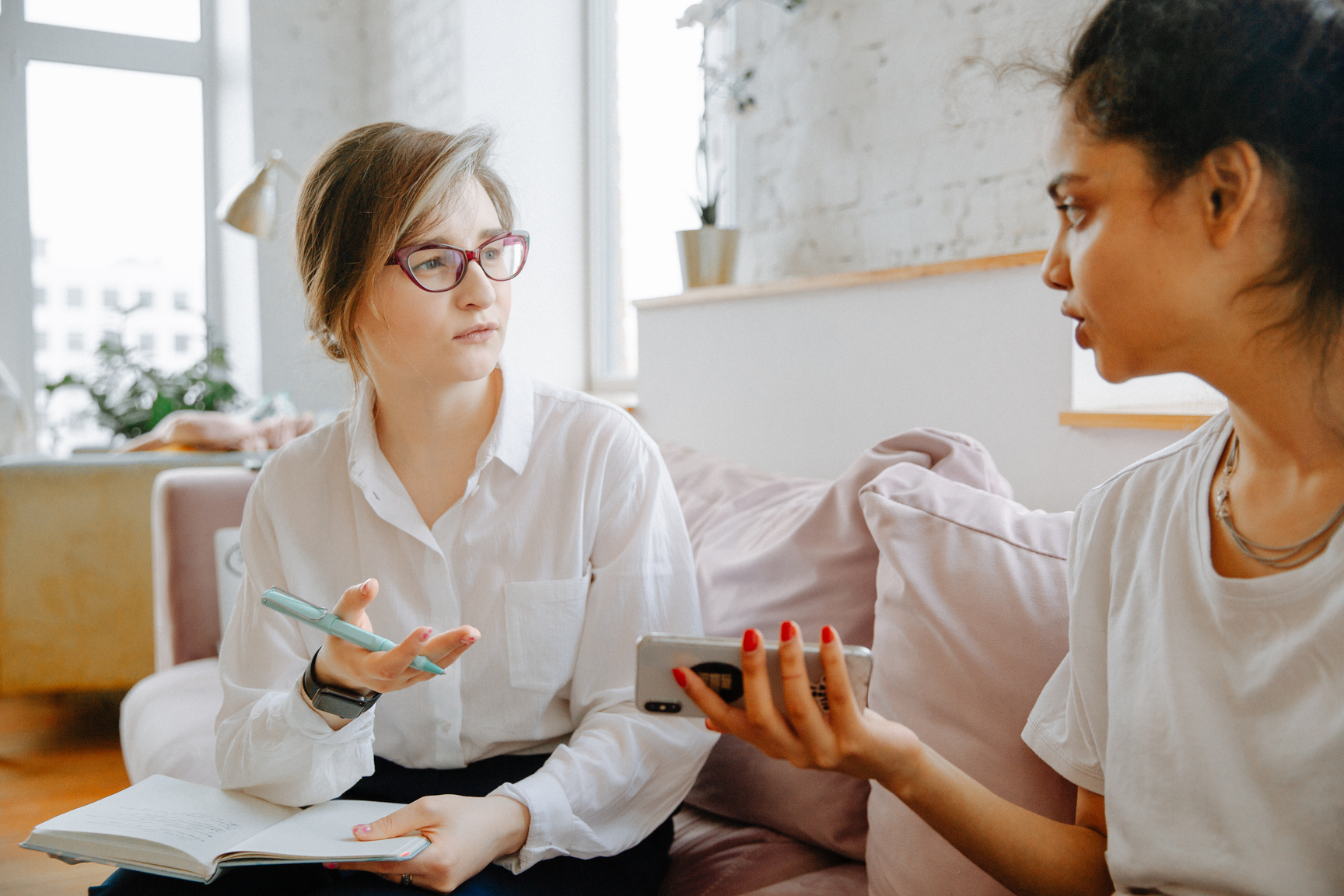 Two individuals sitting on a couch talking to each other