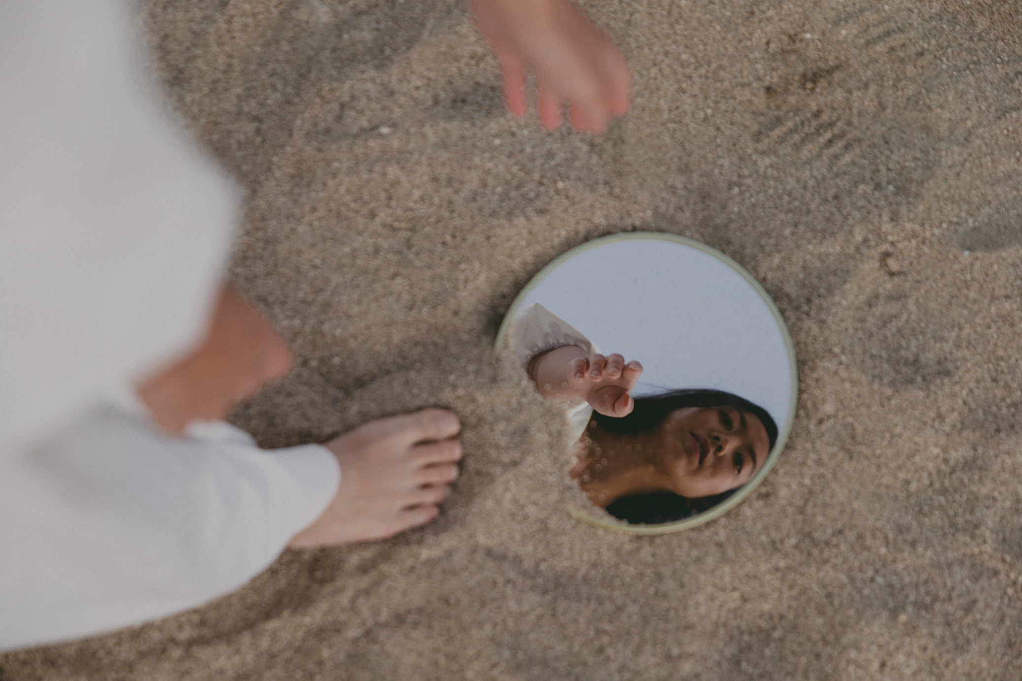 a person standing in the sand with a mirror in front of them