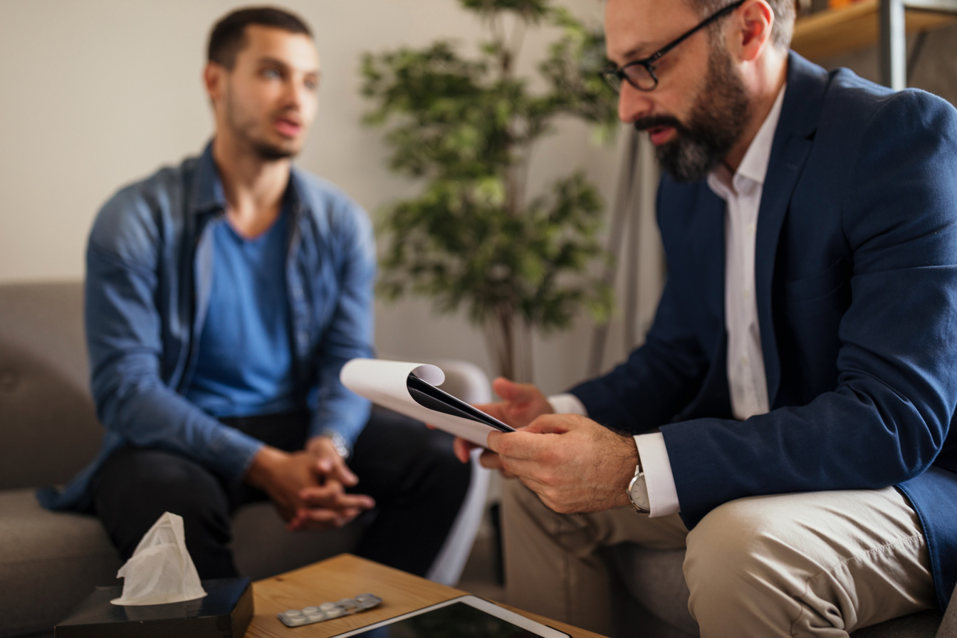 two people sitting on a couch looking at a tablet