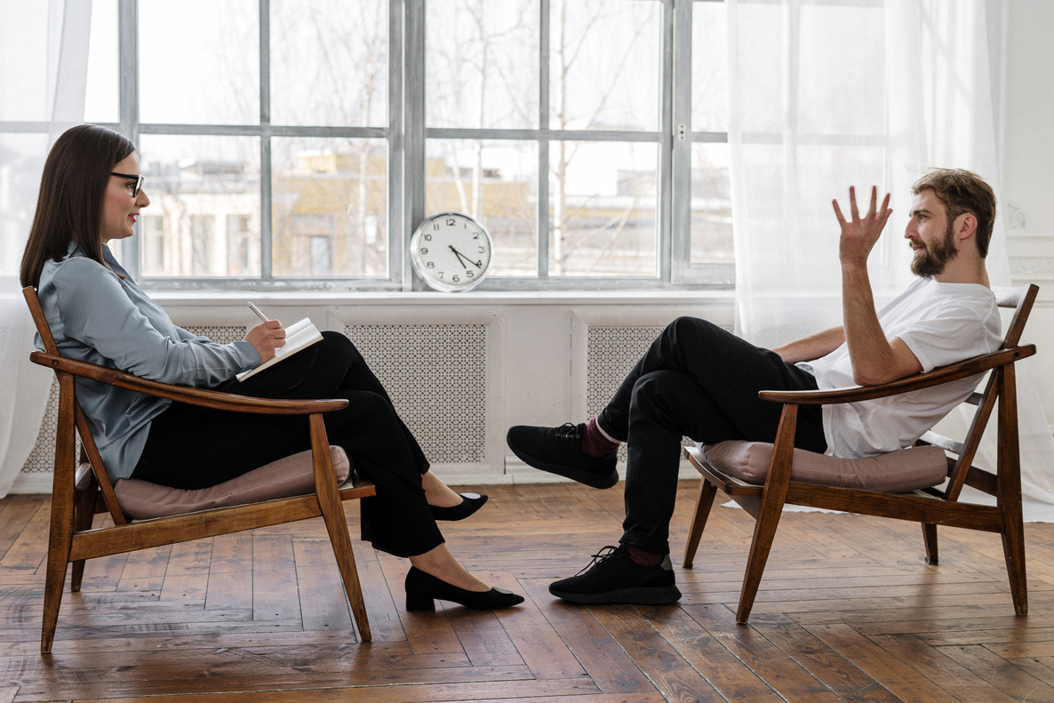 Two people sitting in chairs talking to each other