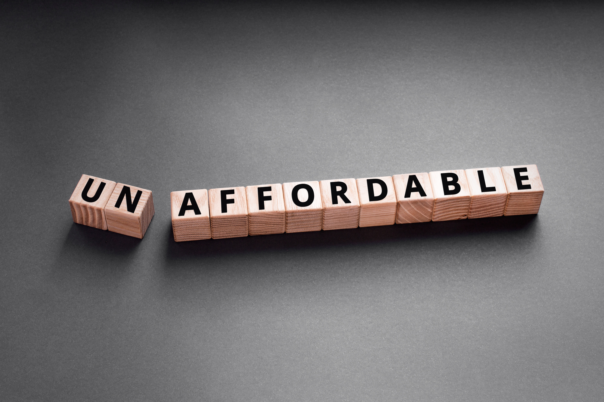 unaffordable is a word made of wooden blocks that spell the word unaffordable on a black background