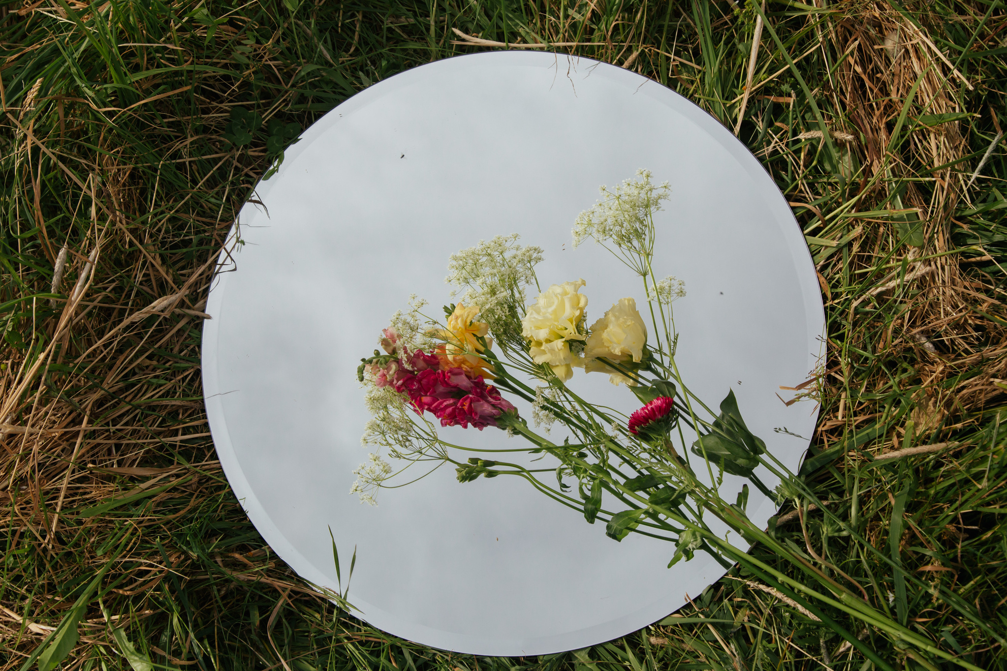 a mirror with flowers on it in the grass