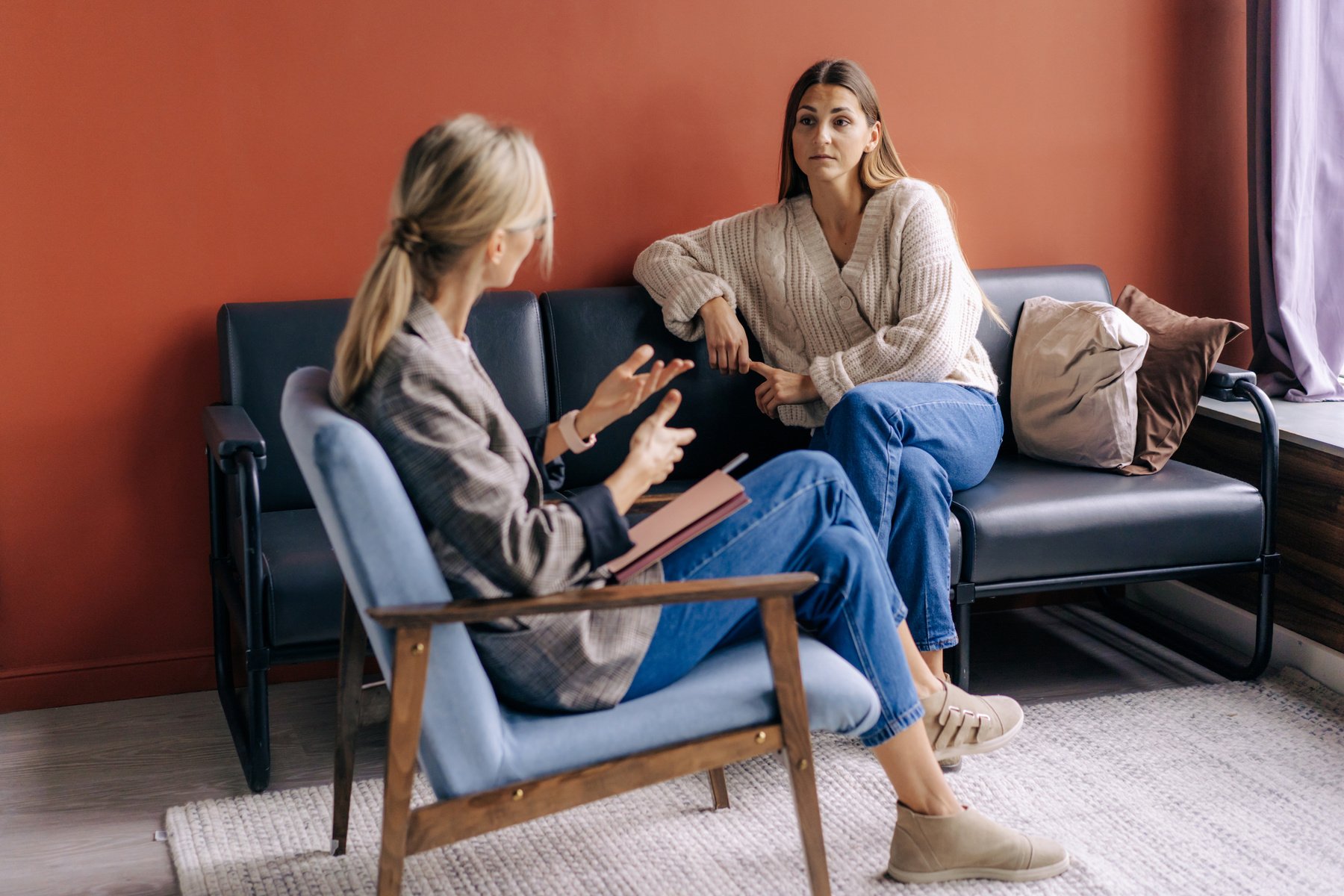 two people sitting on a couch talking to each other