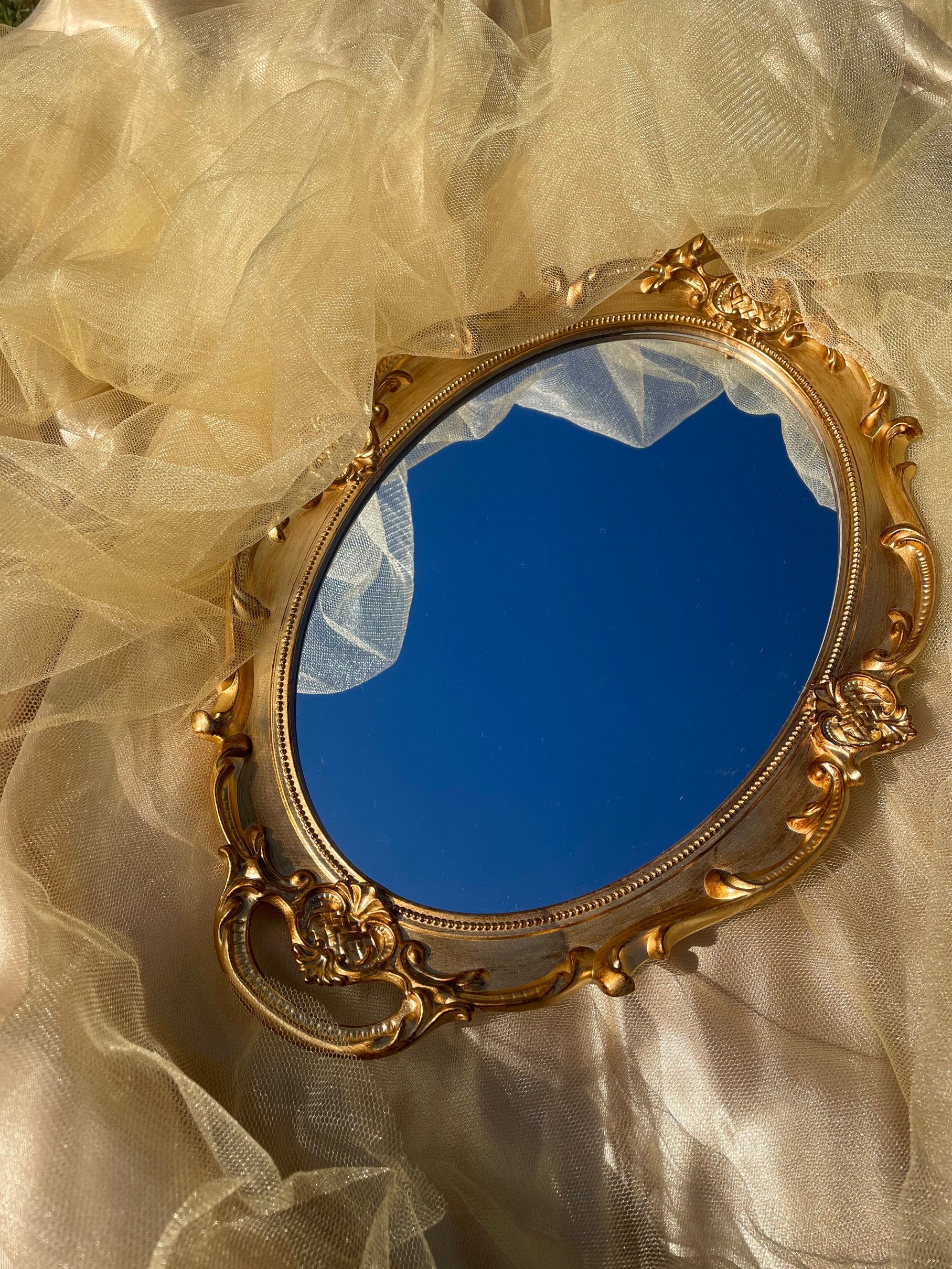 an ornate gold mirror sits on top of a bed