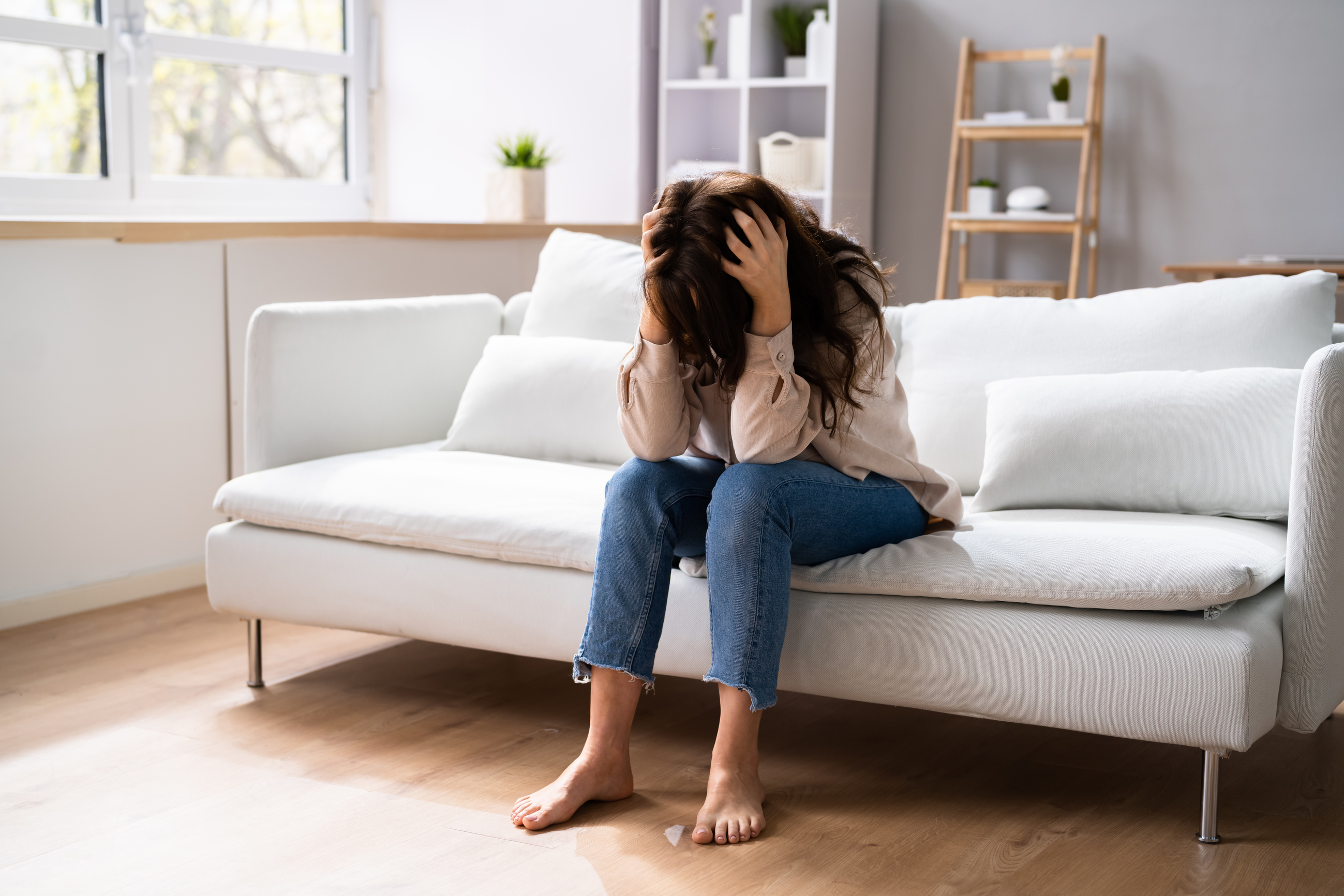 A person sitting on a couch with their head in their hands